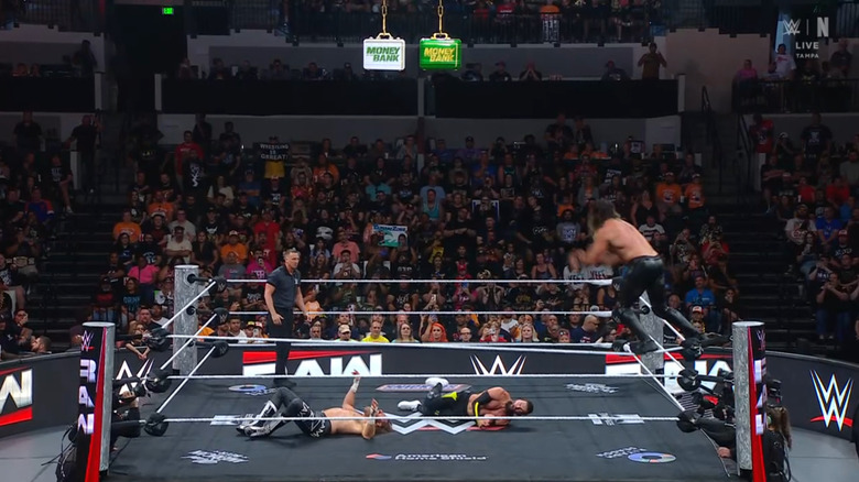 Zayn and Balor in the ring as Rollins is about to take flight off the top rope