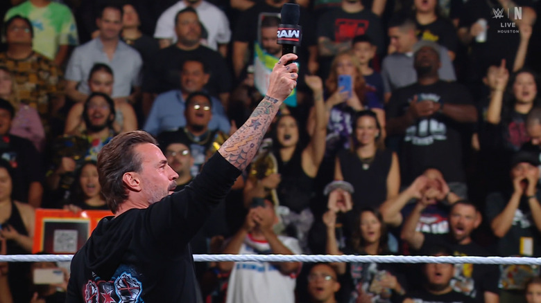 Punk holding up his microphone in the ring