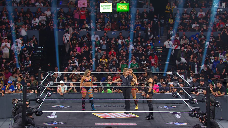 All three women inside the ring as the referee stands in the middle of them