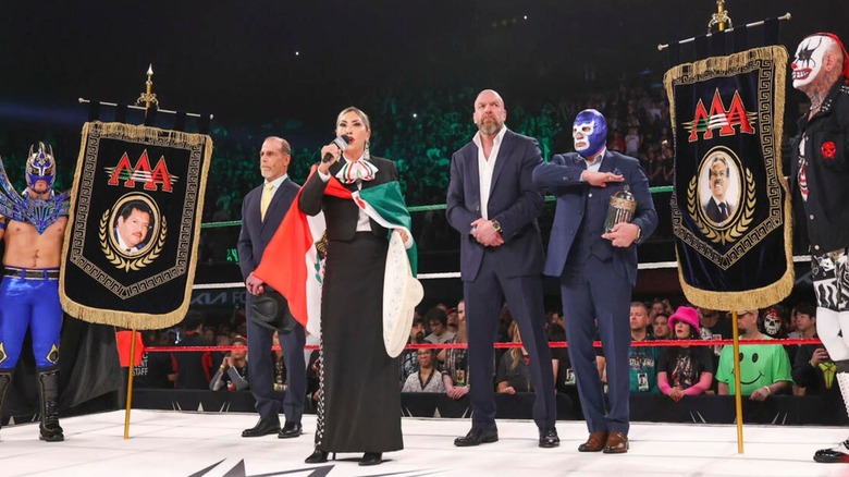AAA and WWE officials stand in the ring as the Mexican national anthem is sung ahead of a WWE x AAA Worlds Collide event.