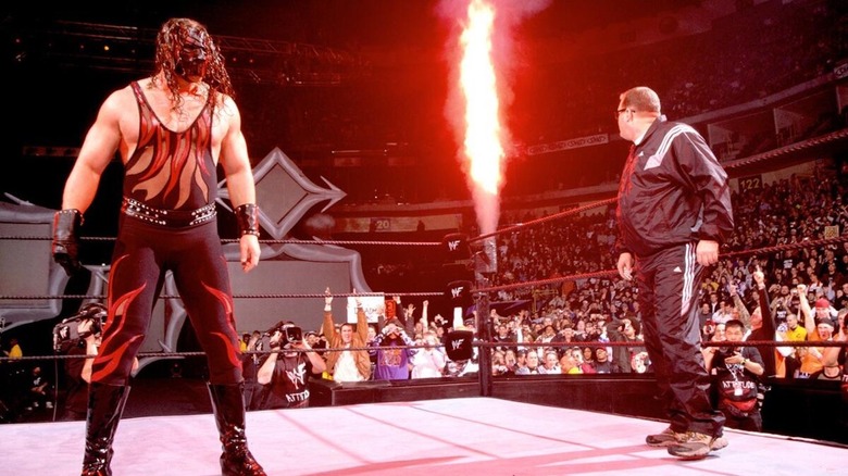 Drew Carey stands in the ring with Kane and his pyro at WWE Royal Rumble 2001