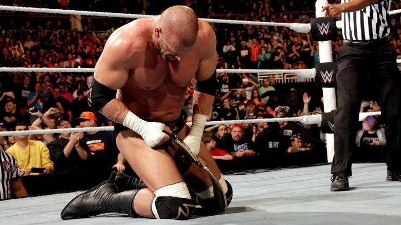 Triple H sits in the ring, clutching the World Heavyweight Championship, after winning the 2016 Royal Rumble.