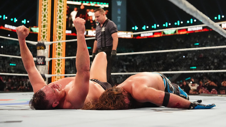 GUNTHER raises his arms while lying beside a fallen AJ Styles at WWE Royal Rumble