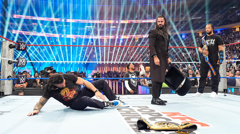 Seth Rollins brandishes a chair between Roman Reigns and Jalen Brunson