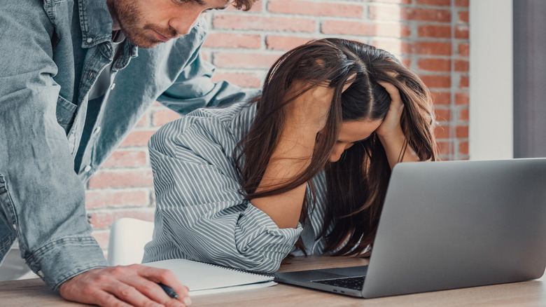 Two young adults look at a computer frustrated.