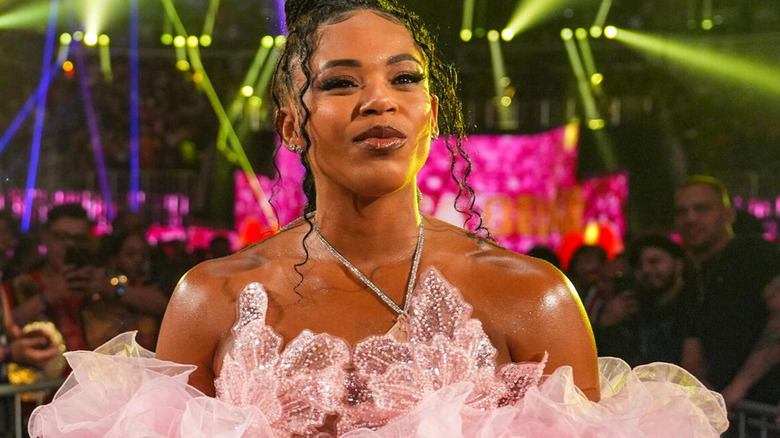 Bianca Belair looks ahead as she returns in a fluffy, pink off-the-shoulder top.