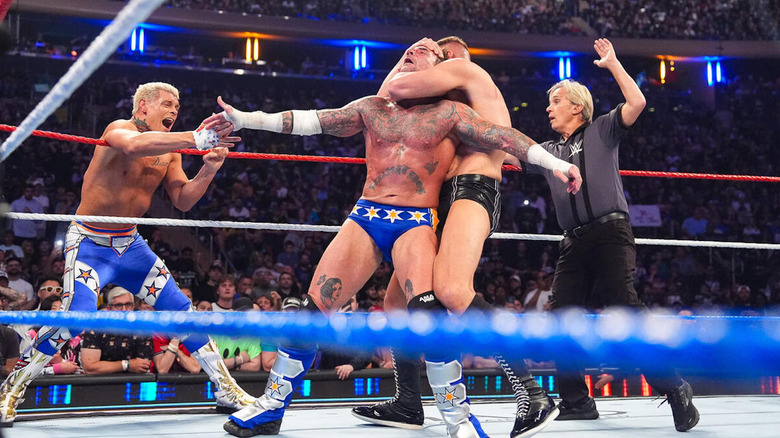 CM Punk reaches for Cody Rhodes, as Gunther cinches in a Sleeper Hold