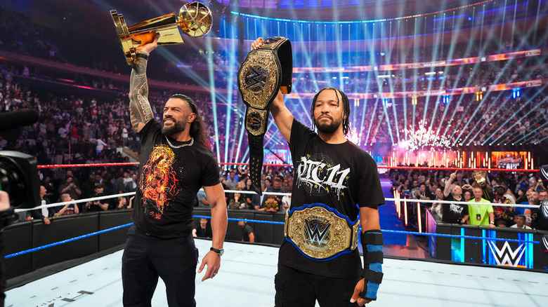 Roman Reigns and Jalen Brunson pose with the NBA Championship Trophy and the World Heavyweight Championship
