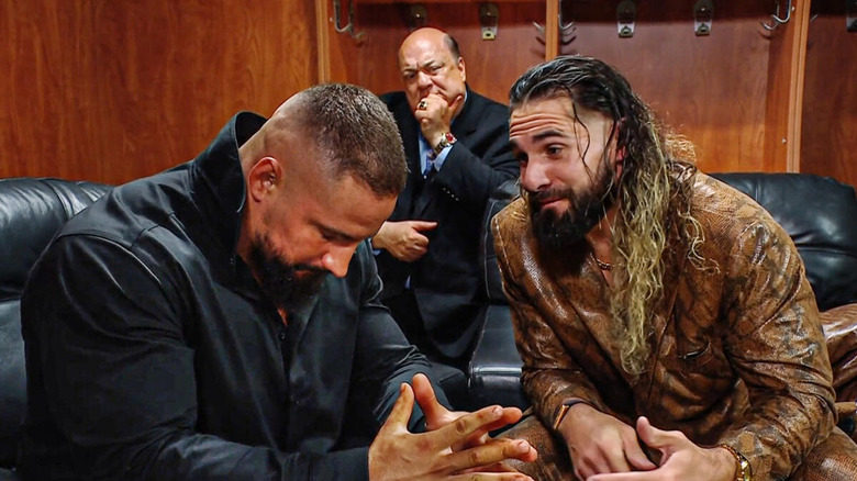 Seth Rollins talking to Bron Breakker backstage, with Paul Heyman in the background