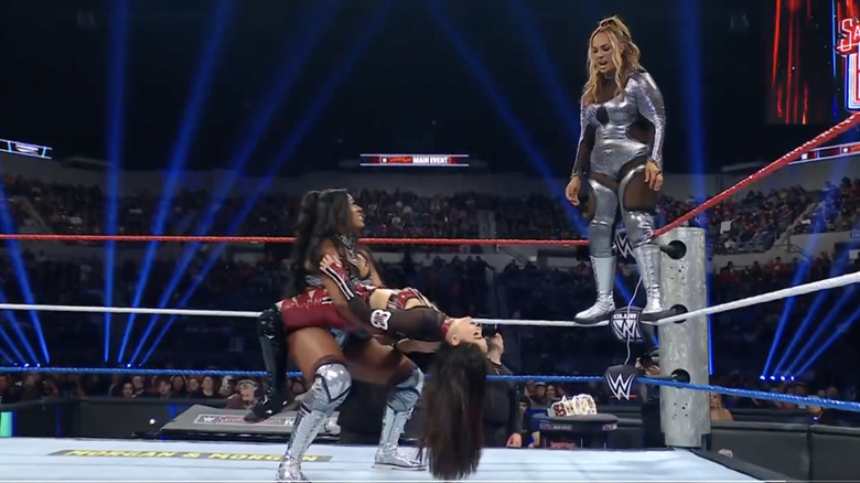 Legend holding Brie in place as Jax stands on the middle rope