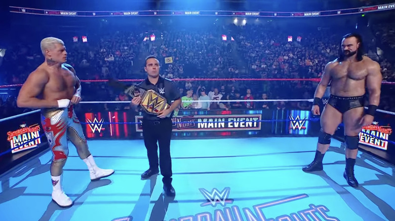 Rhodes and McIntyre staring one another down as the referee holds up the title belt