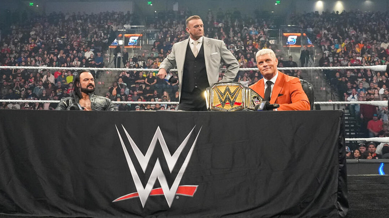 Drew McIntyre and Cody Rhodes sit at a table in the ring beside Nick Aldis on "WWE SmackDown"
