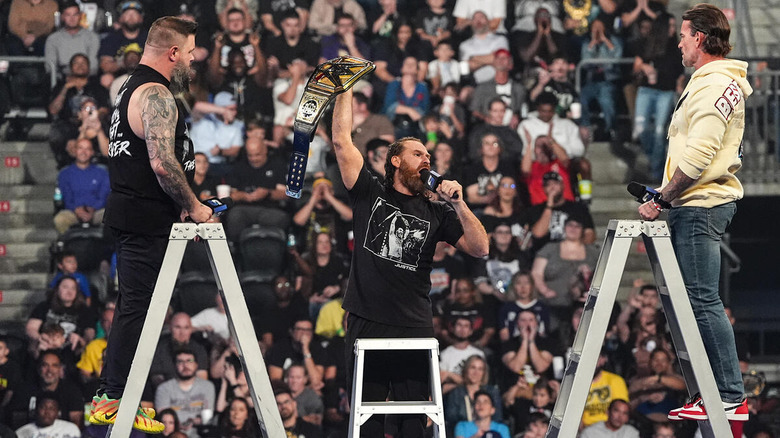 Kevin Owens, Sami Zayn, and CM Punk with microphones on ladder on "WWE SmackDown"