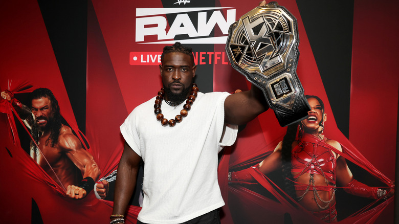 Oba Femi holds up the NXT Title