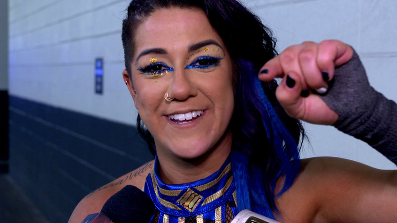 WWE star Bayley points toward the camera while smiling
