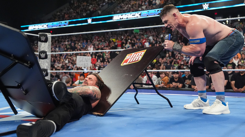 John Cena cuts a promo as Punk is laying on a broken table