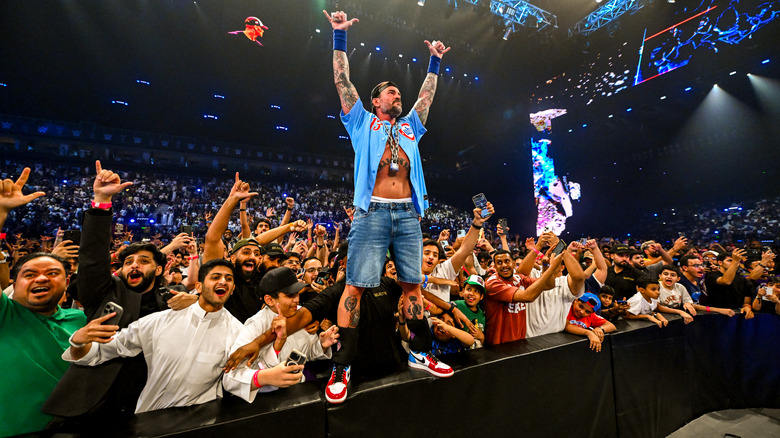 CM Punk dressed up as "Doctor of Thuganomics" John Cena, posing with the crowd in Riyadh on "WWE SmackDown"