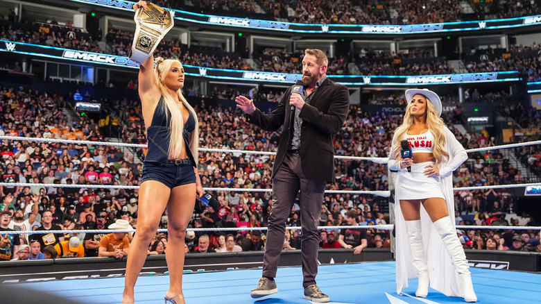 Tiffany Stratton holds up her title belt while in the ring with Wade Barrett and Trish Stratus on "WWE SmackDown"