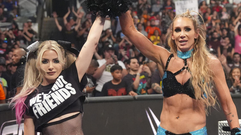 Alexa Bliss holds up Charlotte Flair's hand.