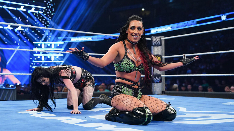 Jacy Jayne kneels in the ring and poses while Paige crawls behind her on "WWE SmackDown"
