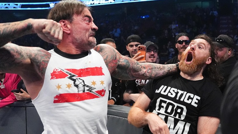 CM Punk pulls back his fist to punch Sami Zayn outside the ring on "WWE SmackDown"