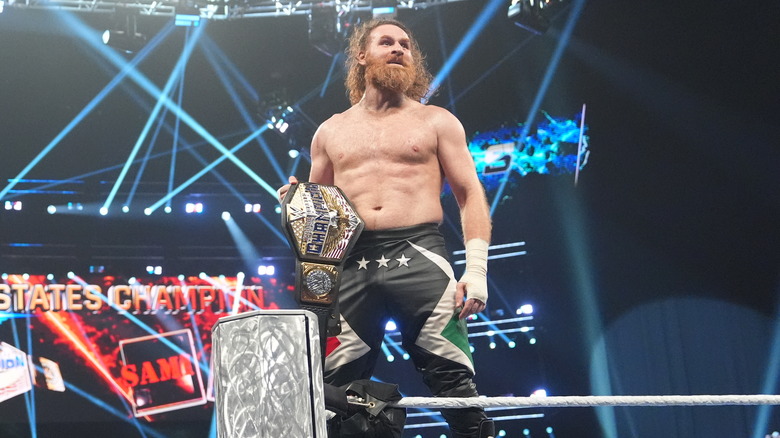 Sami Zayn stands on the middle turnbuckle, United States Championship in hand.