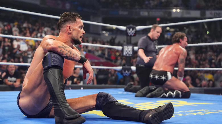 Finn Balor sitting in the ring looking at a kneeling CM Punk on "WWE SmackDown"