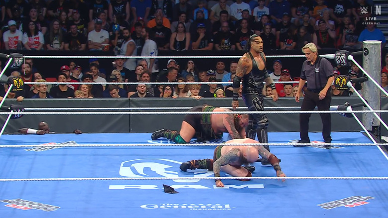 Priest standing over Erik and Ivar in the ring as Truth is on the outside