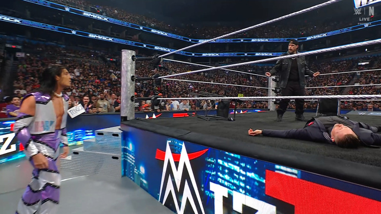 Jelly Roll standing over The Miz as Wilson looks on from the outside.