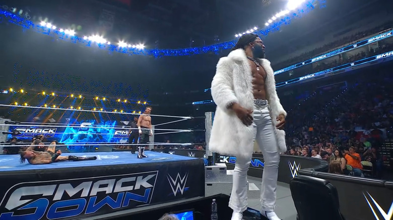 Williams on top of the announce desk as Black and Zayn are in the ring