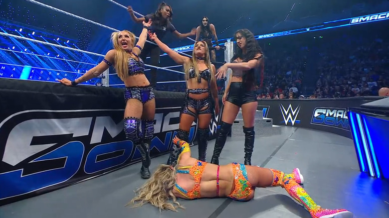 Fatal Influence standing over Flair on the outside as Ripley is behind them on the ropes