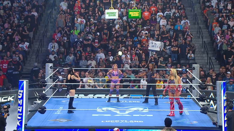 Thre three women staring at the Money In The Bank briefcases suspended above the ring