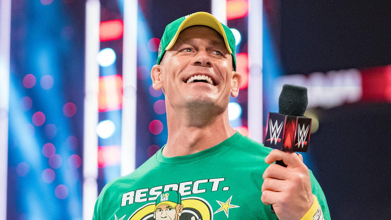 John Cena smiling and holding up a WWE microphone