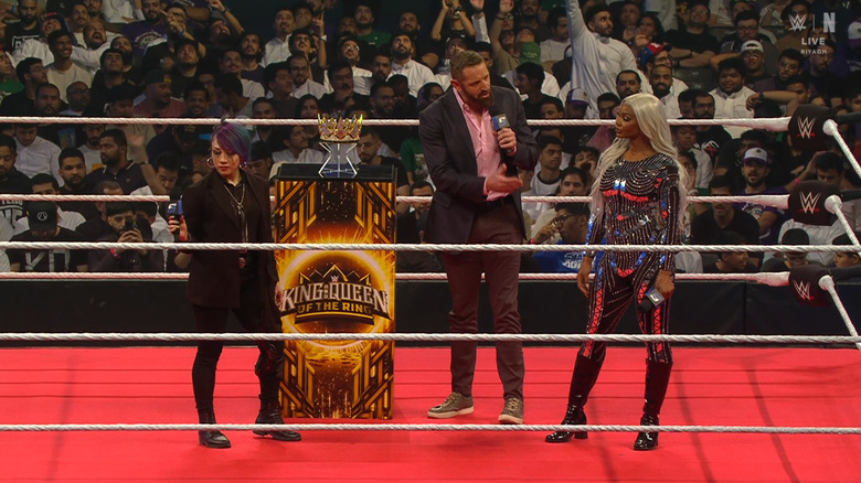 Asuka and Cargill staring one another down in the ring as Barrett mediates the conversation