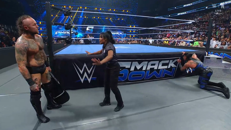 Black with a chair in hand as the referee tries stopping him