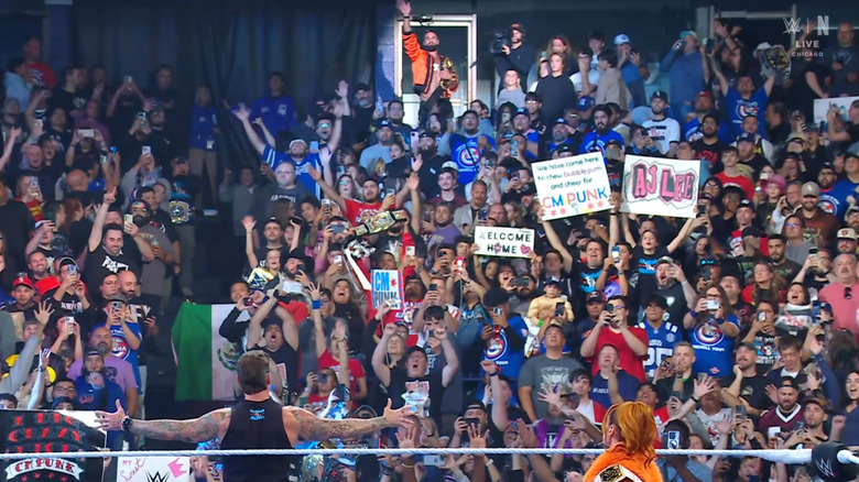 Lynch and Punk in the ring as Rollins stands in the crowd