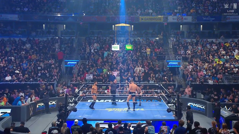 The three men staring down one another in the ring as the briefcase hangs above them