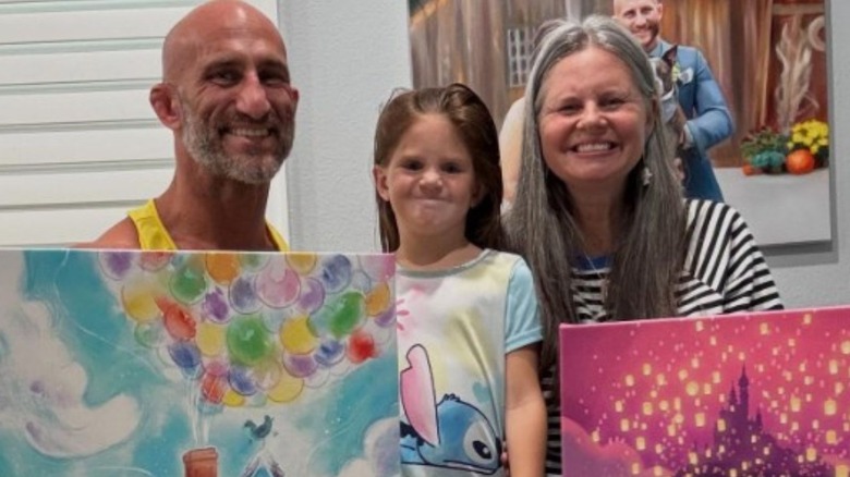 Tommaso Ciampa and his wife, Jessie, pose with their daughter while hold paintings they bought from Disney World in a photo posted to Ciampa's Instagram account.