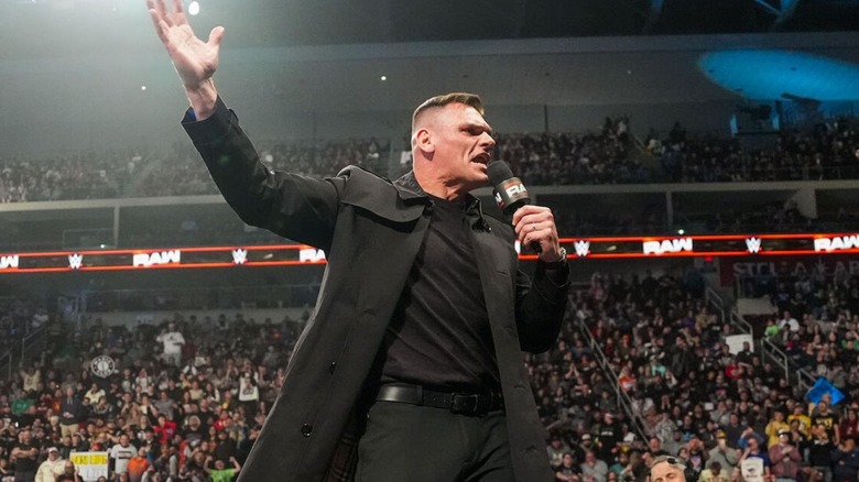 GUNTHER cuts a promo, standing on top of the commentary desk, during the episode of 