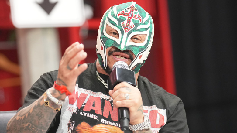 Rey Mysterio sostiene un micrófono.