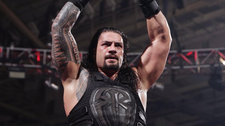 Roman Reigns puts his arms up in his signature "Big Dog" pose.