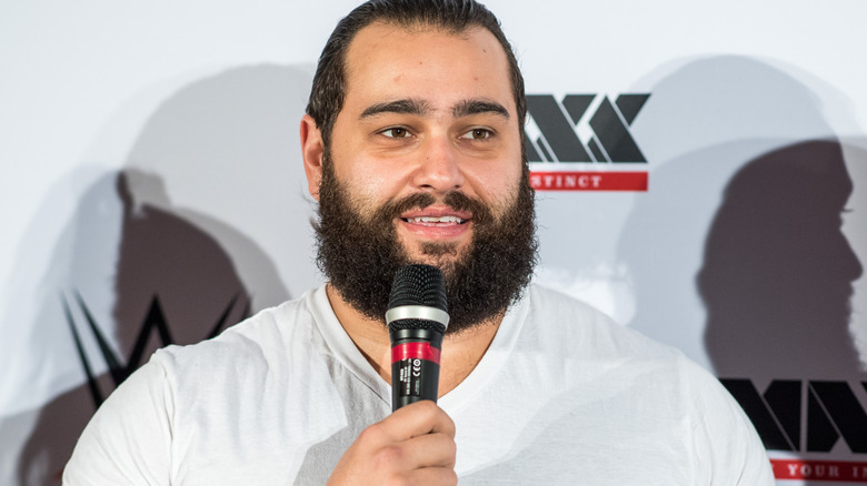 Rusev is holding a microphone