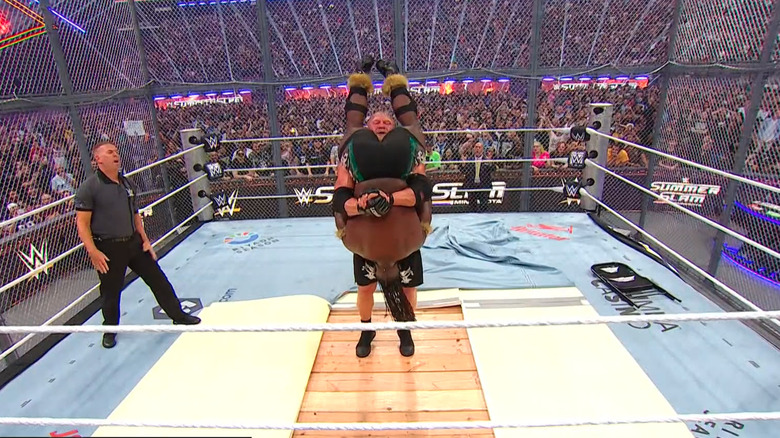 Brock Lesnar prepares to hit Oba Femi with a Tombstone Piledriver on the exposed wood at WWE SummerSlam