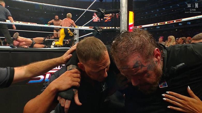 Jelly Roll being helped to the back as McIntyre and Paul beat down Orton in the corner