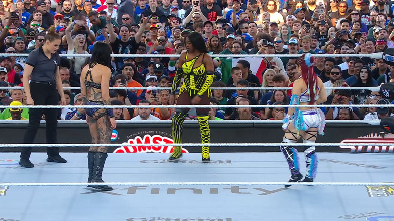Ripley and SKY staring down Naomi in the ring