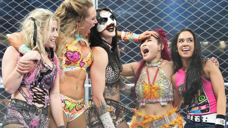 Alexa Bliss, Charlotte Flair, Rhea Ripley, IYO SKY, and AJ Lee celebrate in the WarGames cage post-victory.