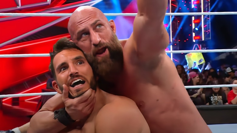 Tommaso Ciampa holds Johnny Gargano's face as he points to the WrestleMania 40 sign.