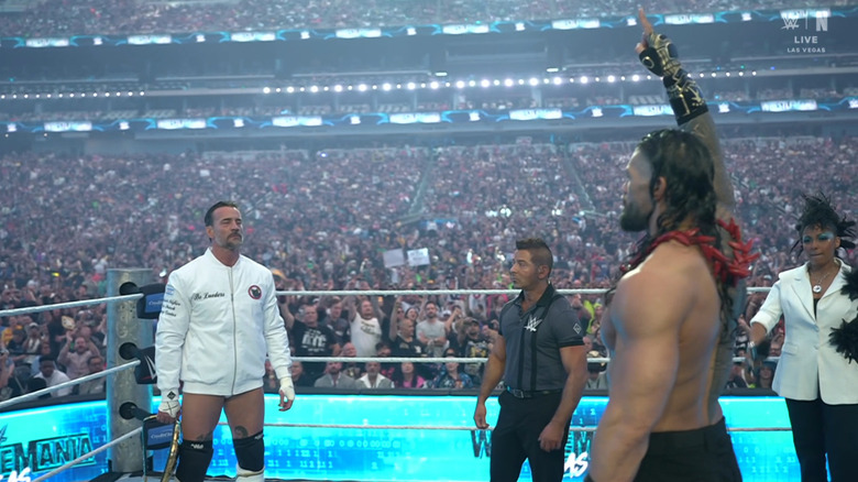 Punk and Reigns in the ring staring each other down during the announcement