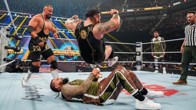 Guest referee LA Knight and Bron Breakker look on as Bronson Reed drops himself on top of Jimmy Uso, while Jey Uso stands in the corner.