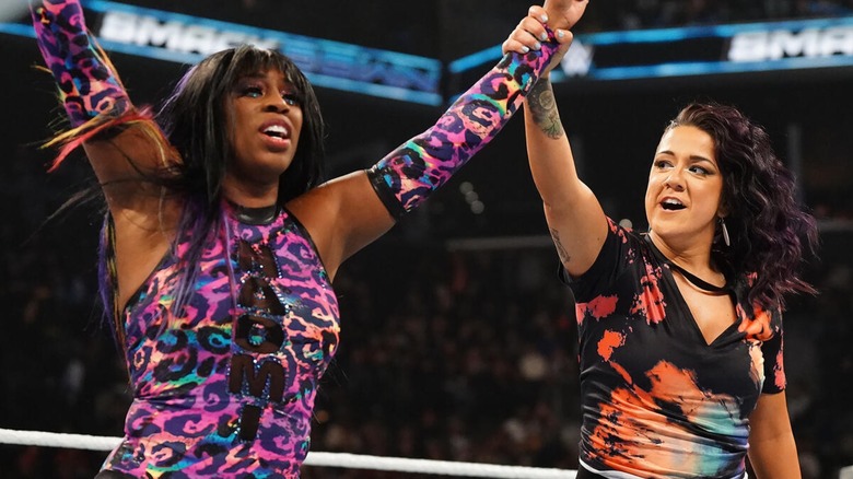 Bayley holding Naomi's arm up after helping her defeat Candice LeRae. "SmackDown," 2024.